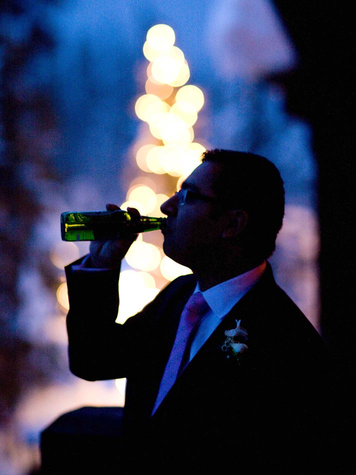 With the snow covered trees lit up in the background one of Steve's friends drinks a beer at the reception.(Photography by Scott Eklund/Red Box Pictures)