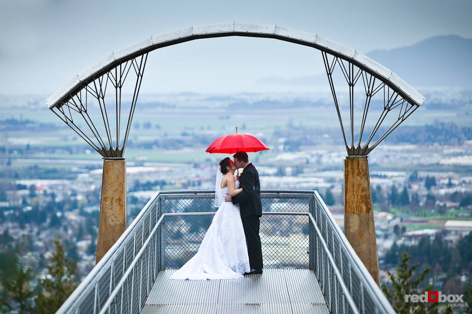 Marilee and Phil stand in the rain overlooking Mt. Vernon, WA from a viewpoint at the top of Little Mountain prior to their wedding at Hillcrest Lodge. (Photography by Andy Rogers/Red Box Pictures)