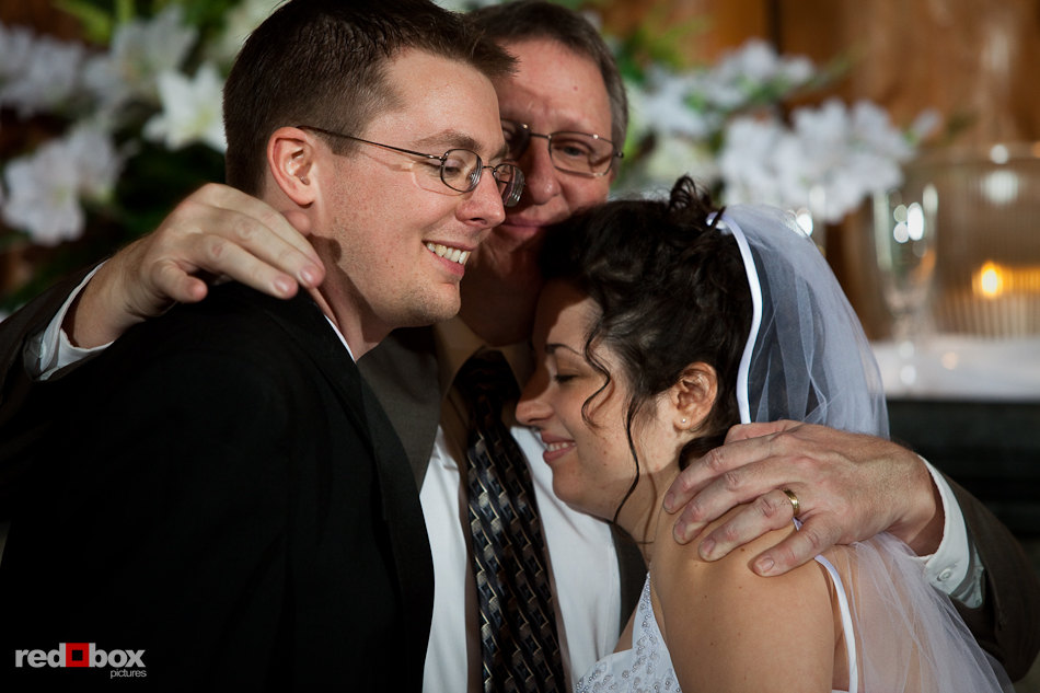 Phil and Marilee get a hug from their officiant after being married at Hillcrest Lodge in Mt. Vernon, WA. (Photography by Rob Sumner / Red Box Pictures)