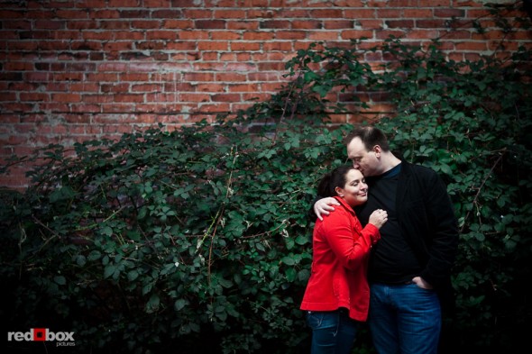 Tara and Brian during their Old Ballard engagement portrait by a brick wall covered in ivy. (Photography by Andy Rogers/Red Box Pictures)