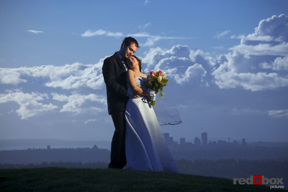 The bride and groom embrace with Seattle in the background at the Golf Club at Newcastle. Scott Eklund/Wedding Photographer/Red Box Pictures