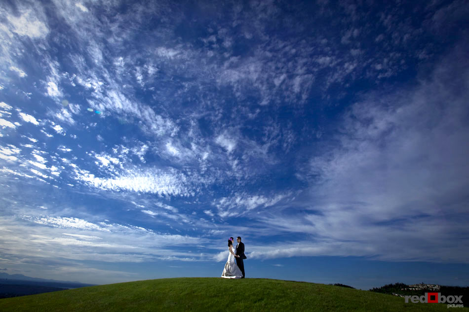 The bride and groom stand atop a hill over looking Seattle and Bellevue from the Golf Club at Newcastle. (Wedding Photography Scott Eklund Red Box Pictures)