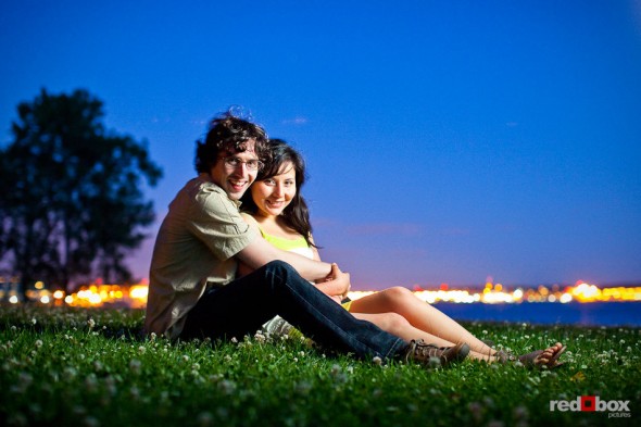 At dusk, Anghi and Andy pose with the glow of West Seattle behind them during an engagement portrait session at Myrtle Edwards Park. Photo by Dan DeLong/Red Box Pictures