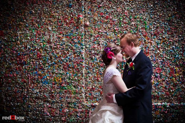 Maureen and Alex kiss by the gum wall in Post Alley at the Pike Place Market prio to their wedding at the Georgetown Ballroom in Seattle. (Photo by Andy Rogers/Red Box Pictures)