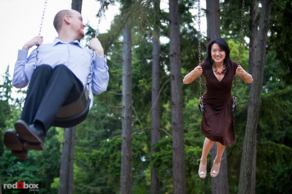 Nobuyo and Rory have fun on the swing set at Seward Park during their engagement portrait session in Seattle. (Photography by Andy Rogers/Red Box Pictures)