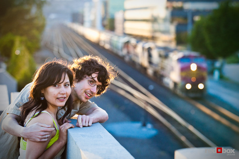 Anghi and Andy watch a freight train during their engagement portrait session in Seattle. Photo by Dan DeLong/Red Box Pictures