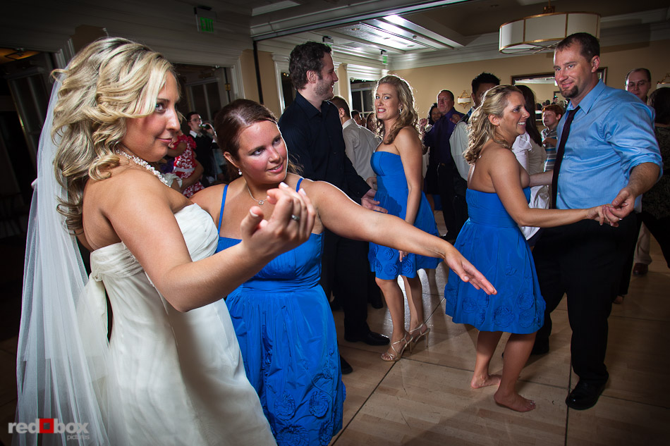 Rachel and a bridesmaid beckon their men onto the dance floor during the wedding reception at the Woodmark Hotel in Kirkland, WA. (Photography by Andy Rogers/Red Box Pictures)