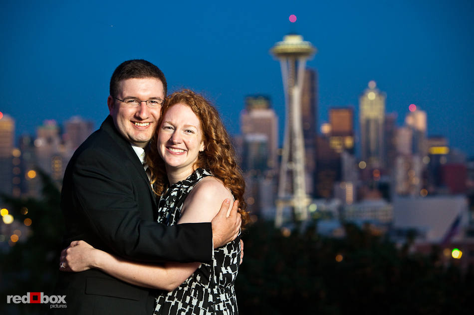 The evening skyline of Seattle is the background for Katherine and Bryan during engagement photo session at Kerry Park. (Photo by Dan DeLong/Red Box Pictures)