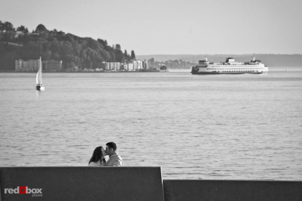Katherine and Bryan kiss as a ferry sails across Elliott Bay during their engagement photo session at the Olympic Sculpture Park in Seattle. (Photo by Dan DeLong/Red Box Pictures)