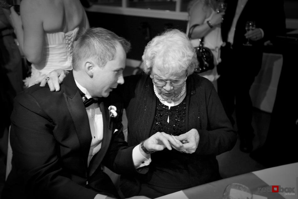 The groom shows his grandmother his wedding ring at the reception following the wedding ceremony at the Top of the Market at the Pike Place Market in Seattle, Wash. Wedding Photography-Scott Eklund-Red Box Pictures-Seattle