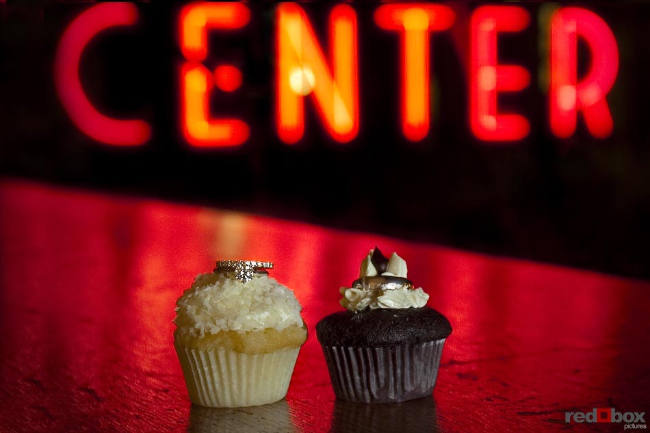 The wedding rings as cupcake toppers with the Pike Place Market neon sign in the background during the wedding at the Top of the Market in Seattle, Wash. Seattle Wedding Photography-Scott Eklund-Red Box Pictures