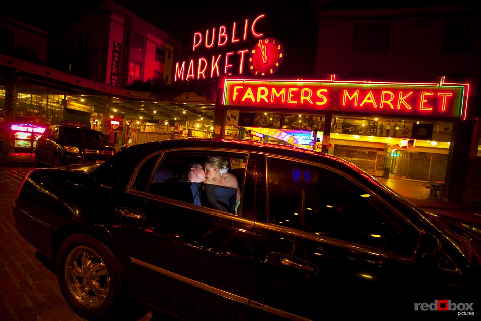 The bride and groom kiss inside the limo in front of the Pike Place Market following their wedding at the Top of the Market in Seattle, Wash. Seattle Wedding Photography-Scott Eklund-Red Box Pictures