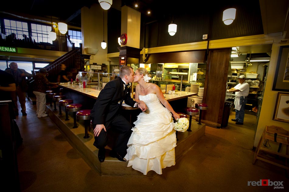 The bride & groom kiss at the counter of The Athenian Inn at the Pike Place Market in Seattle, prior to their wedding at the Top of the Market. Seattle Wedding Photographer-Scott Eklund-Red Box Pictures