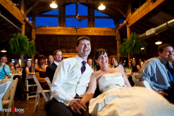 Suzy and Michael enjoy a video of their lives during their wedding reception at Kiana Lodge in Poulsbo, WA. (Photo by Dan DeLong/Red Box Pictures)