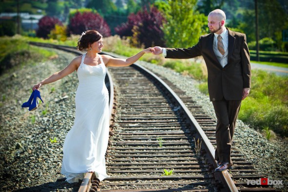 Liz and Ted walk on the railroad tracks near Hidden Meadows in Snohomish, WA before their summer wedding. (Photo by Dan DeLong/Red Box Pictures)
