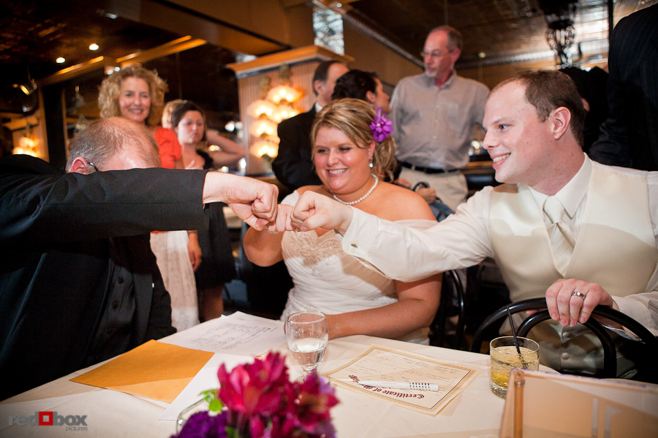Mary and Nick bump fists with their officiant after signing their marriage license during their wedding reception at the Lake Union Cafe in Seattle. (Photography by Andy Rogers/Red Box Pictures)