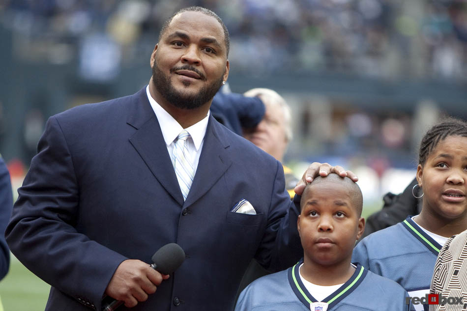 Walter Jones, rests his hand on the top of his son's head as they watch as his number is retired during the two-minute warning of the first half as the Seattle Seahawks beat the Carolina Panthers 31-14 at Qwest Field in Seattle. (Seattle Sports Photography By Scott Eklund/Red Box Pictures)