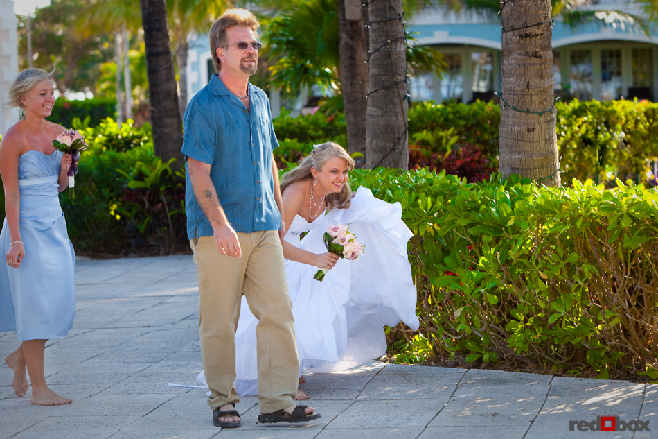 The brides tries to hide from view of her groom as she walks with her father before the wedding at the Old Bay Bahama Resort in the Bahamas. (Wedding Photography by Scott Eklund/Red Box Pictures)