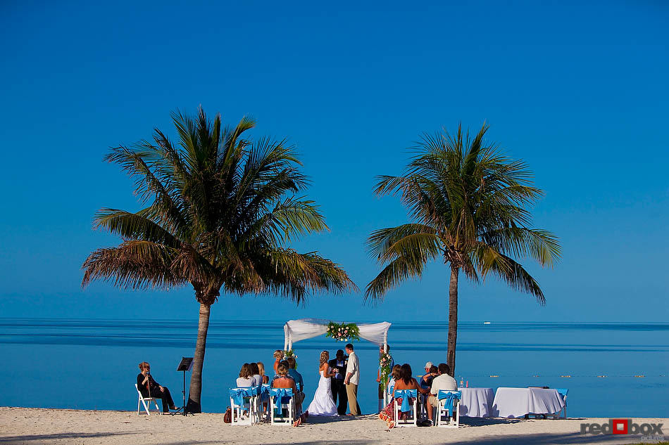 The bride and groom exchange vows under the palm trees during their wedding at the Old Bay Bahama Resort in the Bahamas. (Wedding Photography by Scott Eklund/Red Box Pictures)