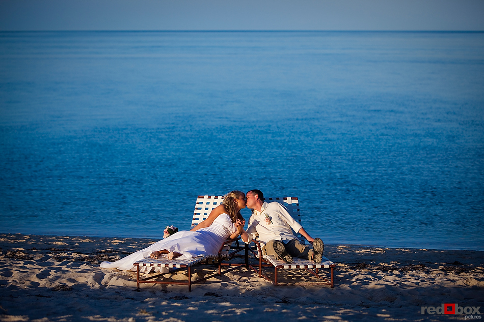 The bride and groom share a kiss while relaxing on the beach after their wedding at the Old Bay Bahama Resort in the Bahamas. (Wedding Photography by Scott Eklund/Red Box Pictures)