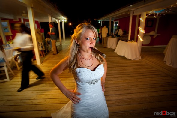 Tasha takes a few puffs on a cigar at her reception at the Old Bahama Bay Resort in the Bahamas. Wedding Photography by Scott Eklund/Red Box Pictures
