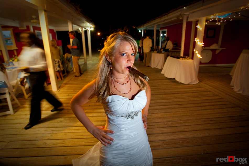 Tasha takes a few puffs on a cigar at her reception at the Old Bahama Bay Resort in the Bahamas. Wedding Photography by Scott Eklund/Red Box Pictures