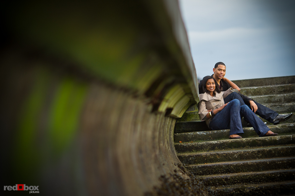 Nick and Tia sit on the stairs to Alki Beach in West Seattle during their engagement photo session. (Photography by Andy Rogers/Red Box Pictures)