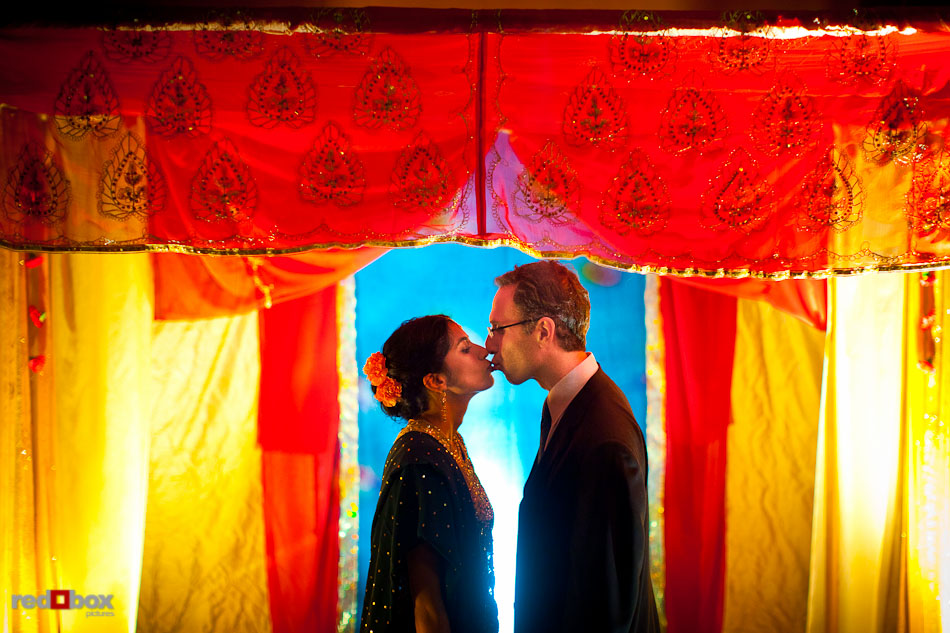 Karthik and Mike kiss beneath the canopy where their Hindu and Jewish wedding ceremonies took place at the Uptown Hideaway in Seattle. (Photo by Dan DeLong/Red Box Pictures)
