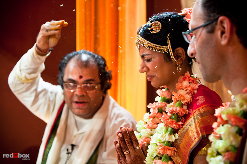 Pundit Mahesh Shastri tosses rice toward Karthik and Mike during their Indian wedding ceremony at the Uptown Hideaway in Seattle. (Photography by Andy Rogers/Red Box Pictures)