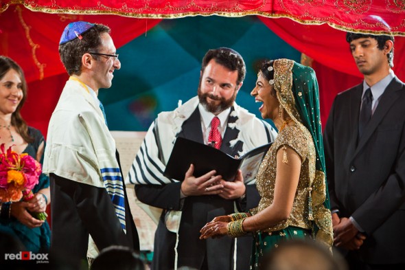 Mike and Karthik laugh as Rabbi Olivier Benhaim performs their Jewish wedding ceremony at the Uptown Hideaway in Seattle. (Photography by Andy Rogers/Red Box Pictures)