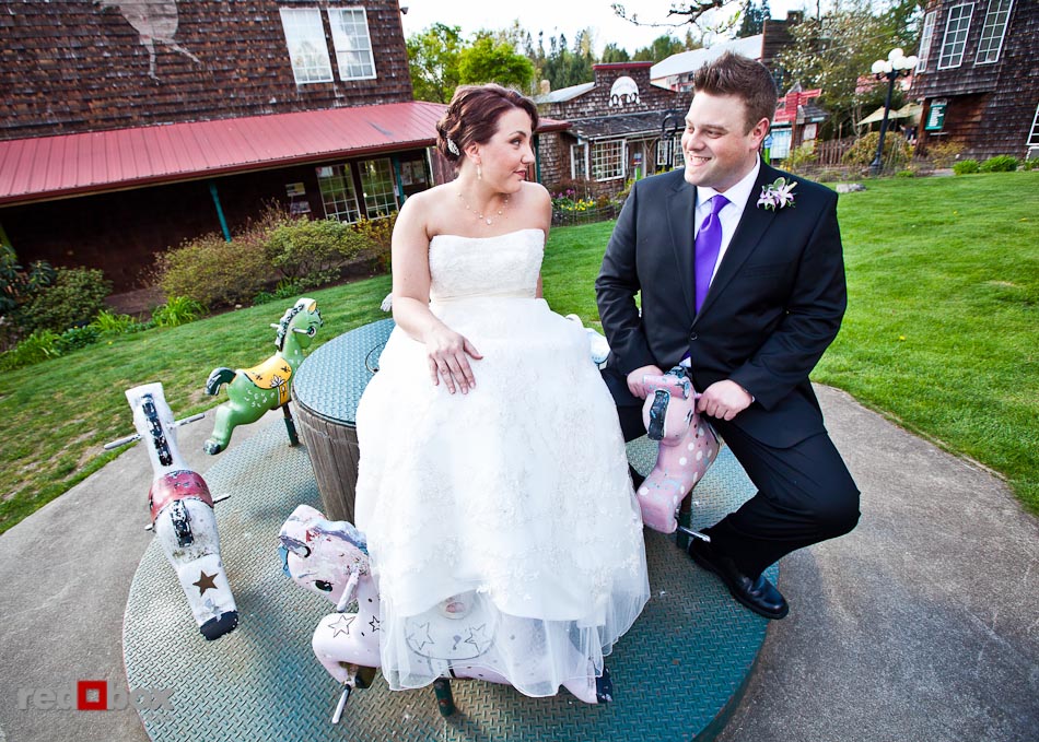 Kari and Matt ride a pint-sized merry-go-round in the Country Village prior to their wedding at Courtyard Hall in Bothell. (Photo by Andy Rogers/Red Box Pictures)