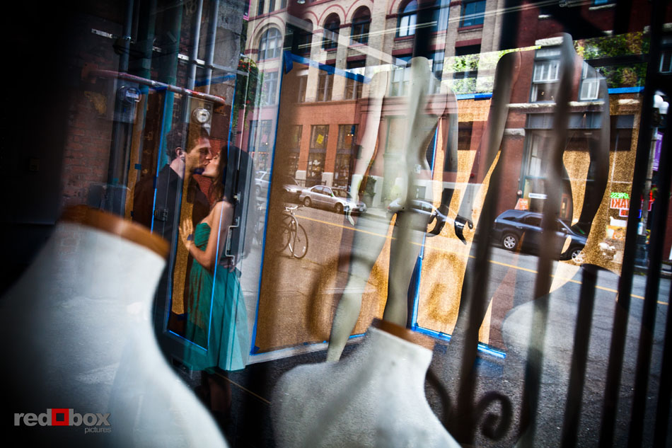 Sharisse and Craig are seen through the windows of a Pioneer Square store during their Seattle engagement photo session. (Photos by Andy Rogers/Red Box Pictures)