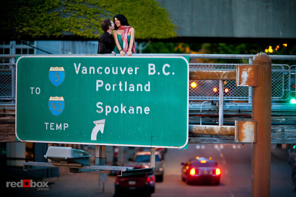 Sharisse and Craig kiss above an Interstate-5 sign during their engagement photos at the ferry terminal in Seattle. (Photos by Andy Rogers/Red Box Pictures)