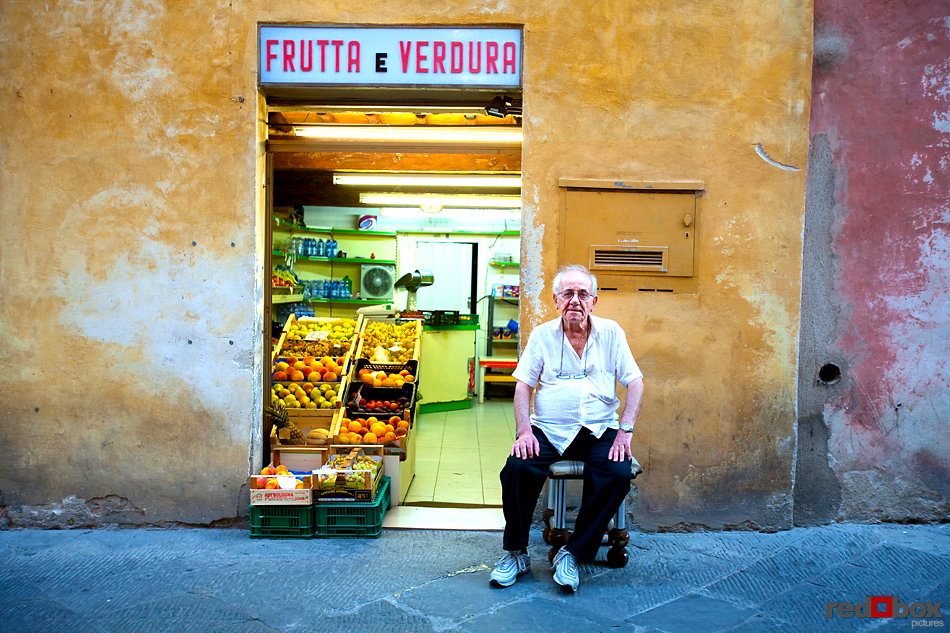A shop owner sits in front of his fruit stand in Siena,Tuscany, Italy. (Italy Photography By Scott Eklund/Red Box Pictures)