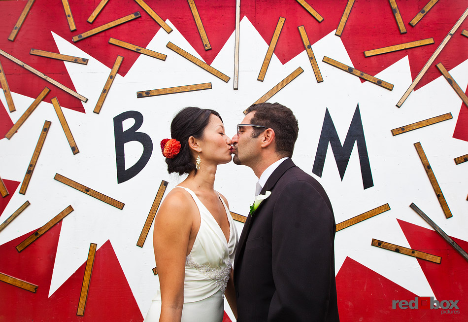 Jane and Kia kiss in front of E T Marsden's artwork that graces the enclosure of the light rail construction site at Cal Anderson Park in Seattle prior to their wedding at Velocity Dance Center in Seattle. Thanks to the artist for making this photo possible: http://www.etmarsden.com/art (Photo by Andy Rogers/Red Box Pictures)