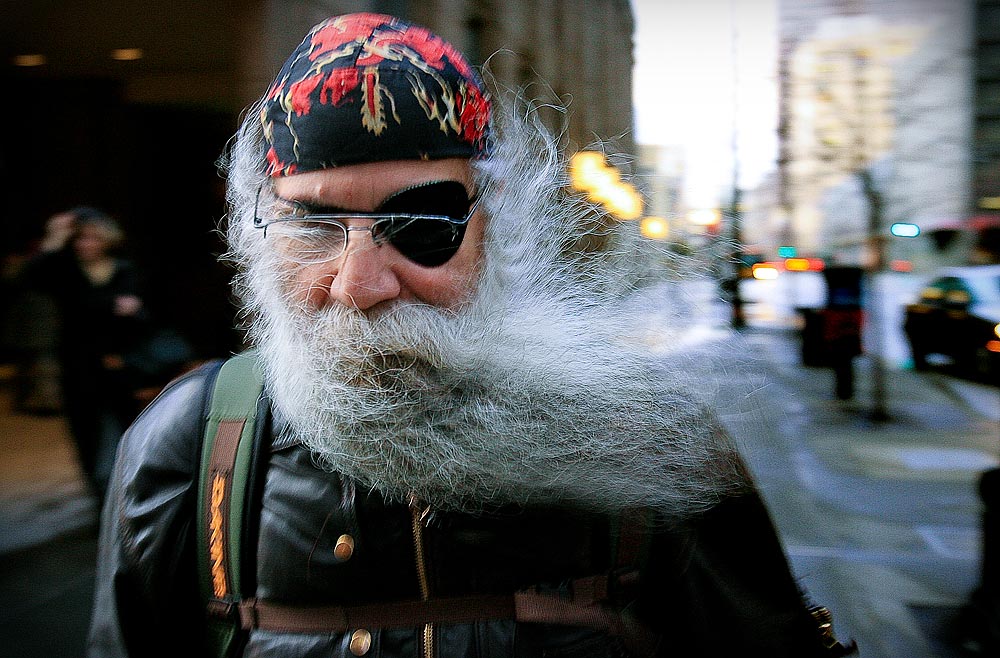 A strong gust of wind sends Frank Zamfino's beard flying as he walks along Third Avenue in downtown Seattle (Photographer: Dan DeLong)