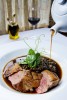 Ripasso duck jus poured over Anatra Alla Lenticchia, a seared duck breast with lentils, pancetta, duck confit and pea vines at La Dolce Vita in Seattle. (Photographer: Andy Rogers)