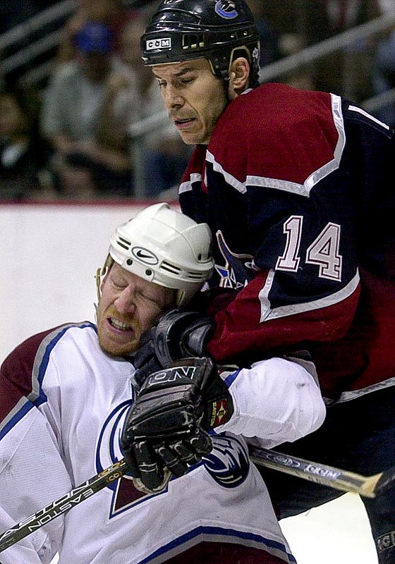 Colorado's Mike Keane takes a hit to the face from Vancouver's Scott Lachance. (Photographer: Andy Rogers)